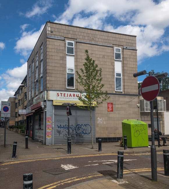 A wide view of a busy street on Streatham High Road showing a mix of commercial and residential buildings, with a row of shops on the left, some with decorative brick facades and large window displays